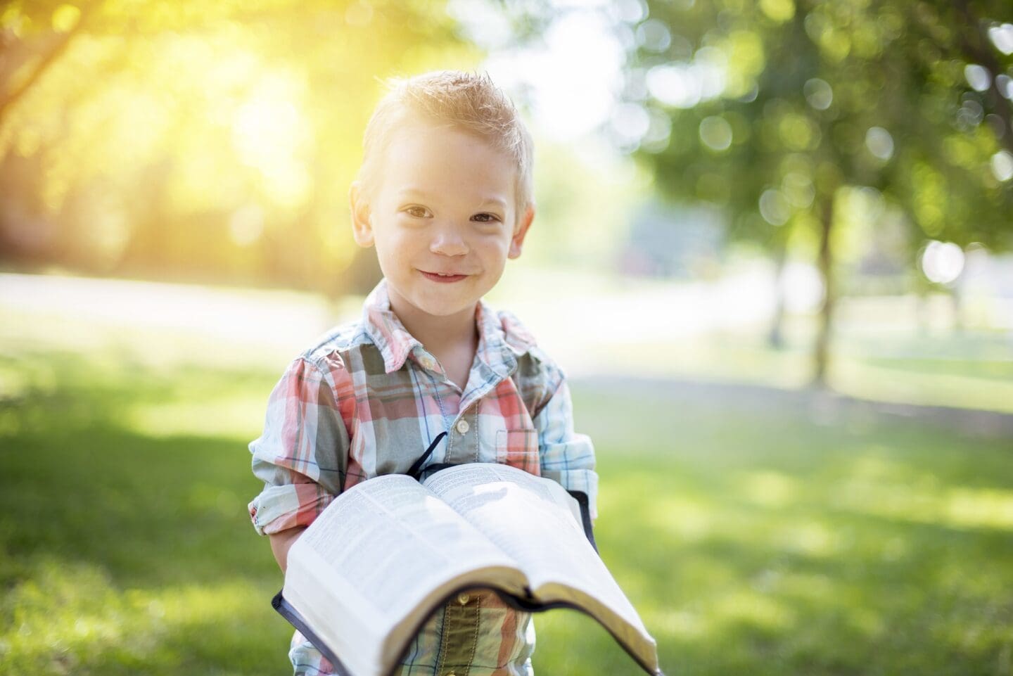 kid reading bible outside